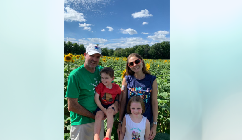 TrialNet participant Amanda Gilchrist along with her spouse and two young children pause for a family picture in a field of yellow sunflowers