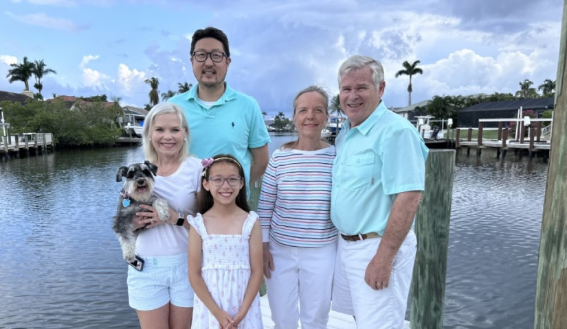 DECA Executive Director Terry posing for a photo with family members on a dock: wife, daughter, son-in-law, grandchild, and dog