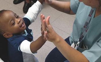 A nurse and a small child double high-fiving