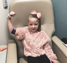 Chica sonriente flexionando su bíceps después de que le extraen sangre