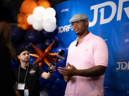 Orlando Brown, Jr. speaks to reporters in front of a blue JDRF backdrop with orange and white ballons